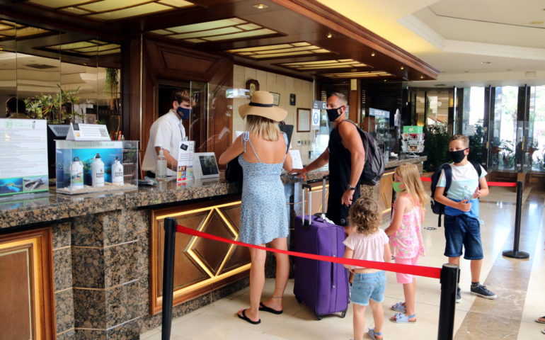 Pla general d'una família estrangera realitzant el check-in a l'hotel Evenia Olympic de Lloret de Mar. Imatge del 29 de juliol del 2020. Foto: ACN - Eli Don